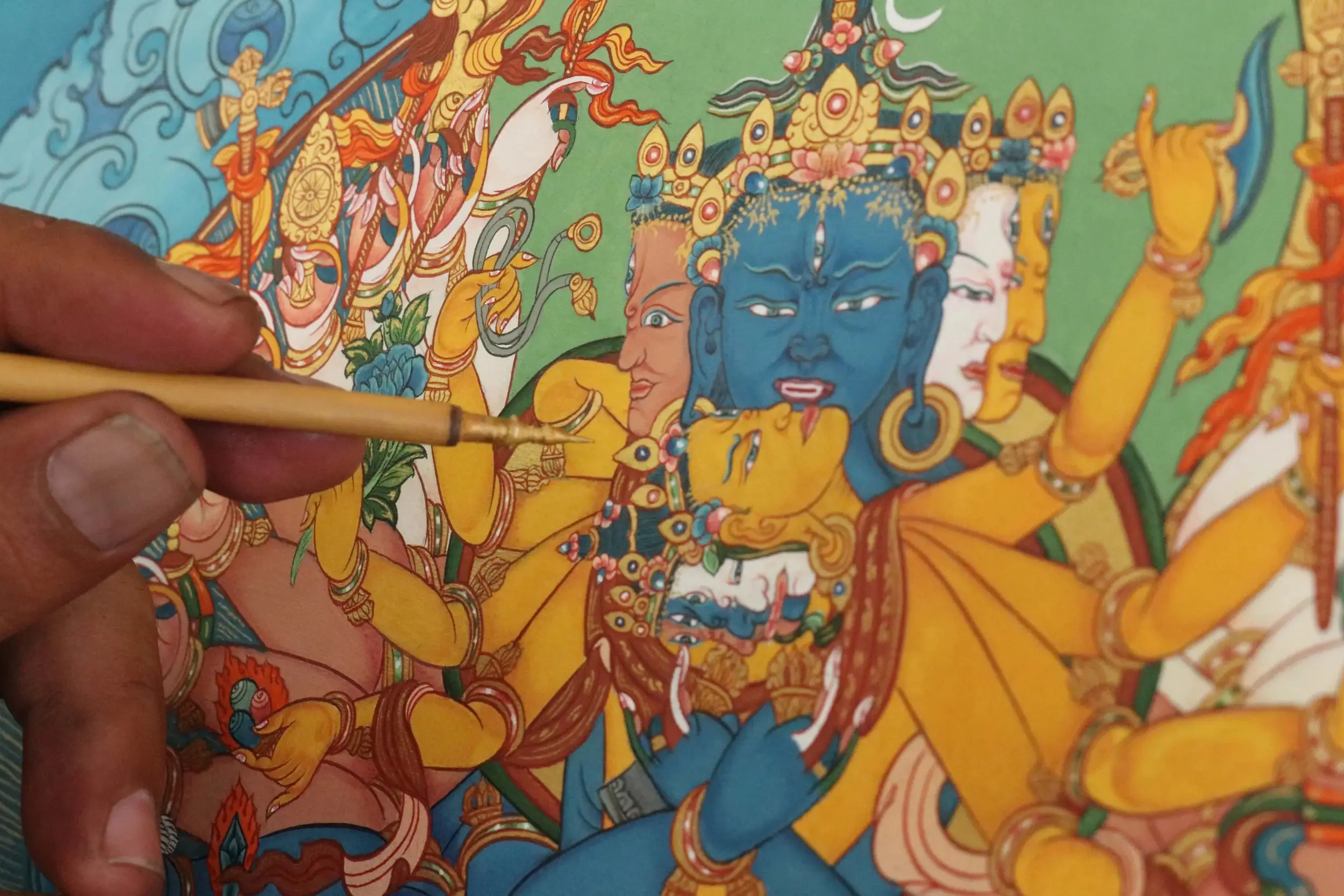 Artisans meticulously painting a traditional Tibetan thangka, showcasing the rich heritage of thangka art.